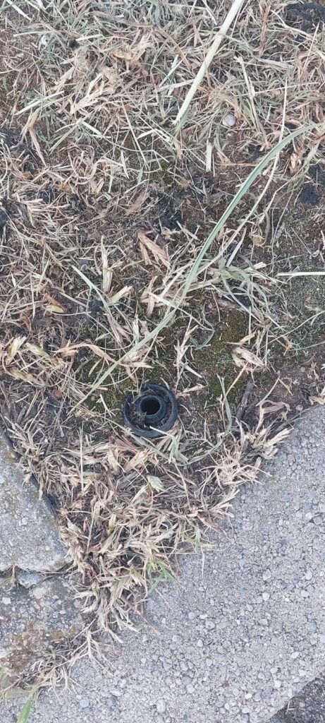 un dettaglio dell'impianto di irrigazione rotto in un'aiuola pubblica.