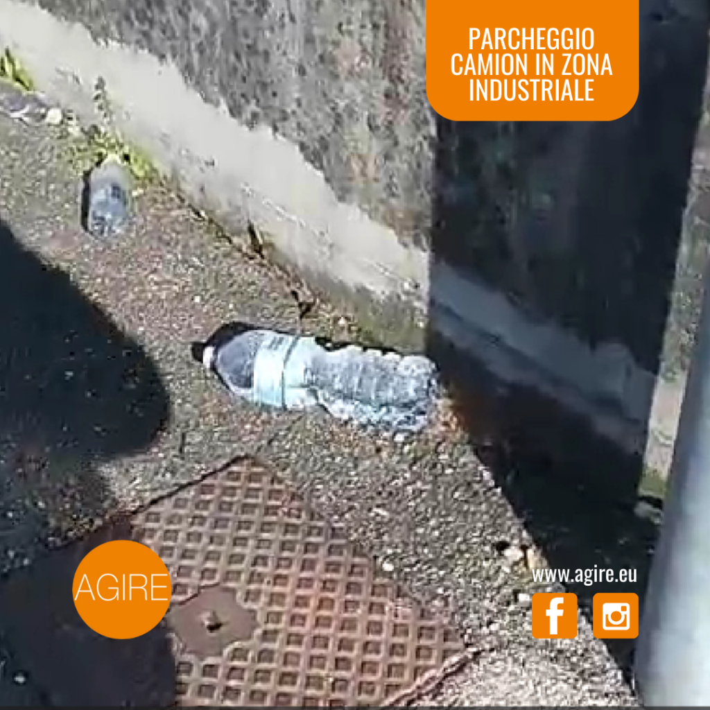 rifiuti abbandonati in zona industriale: il dettaglio di una bottiglia.